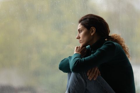 side view frustrated thoughtful woman looking out rainy window