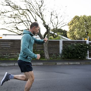 side view man running on suburban street early morning checking smart watch