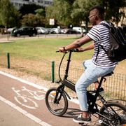 side view of a young african american male student riding a bicycle