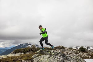 side view of fit active man trail running on mountain ridge