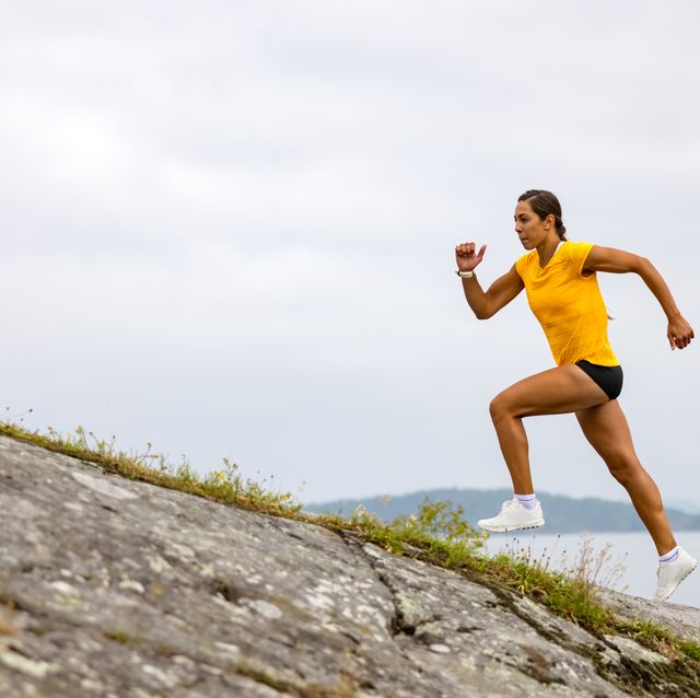side view of fitness woman doing high intensity running on mountainside by the sea