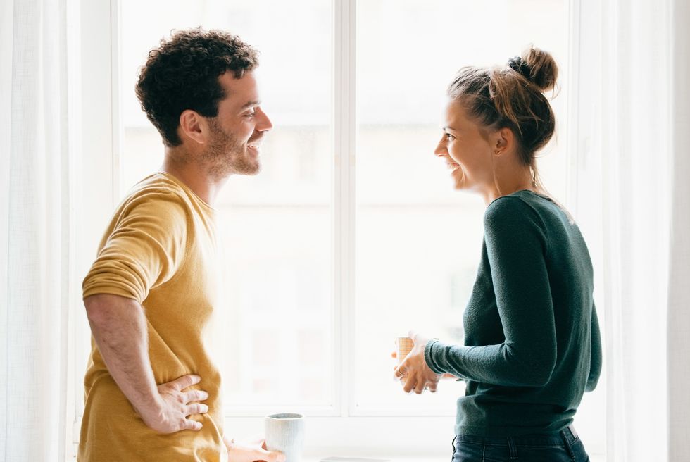 side view of happy couple talking while standing by window at home