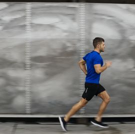 side view of mid adult man in sports clothing running in city