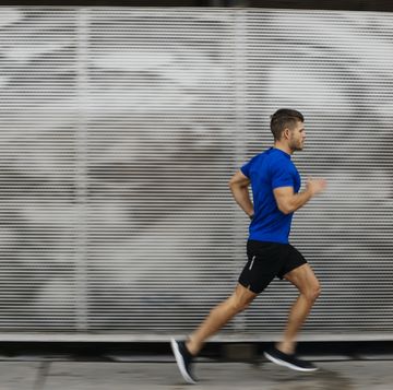side view of mid adult man in sports clothing running in city