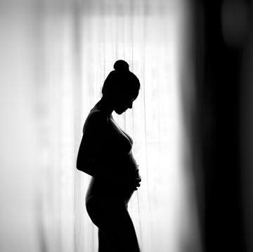 side view of silhouette pregnant woman standing by window at home