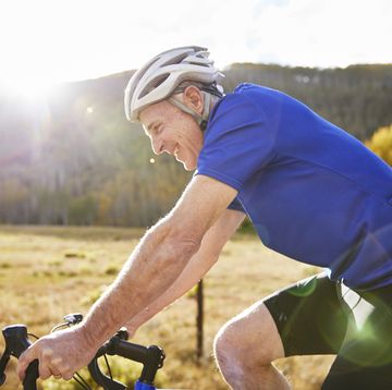 longevity tests side view of smiling senior man riding bicycle during sunny day