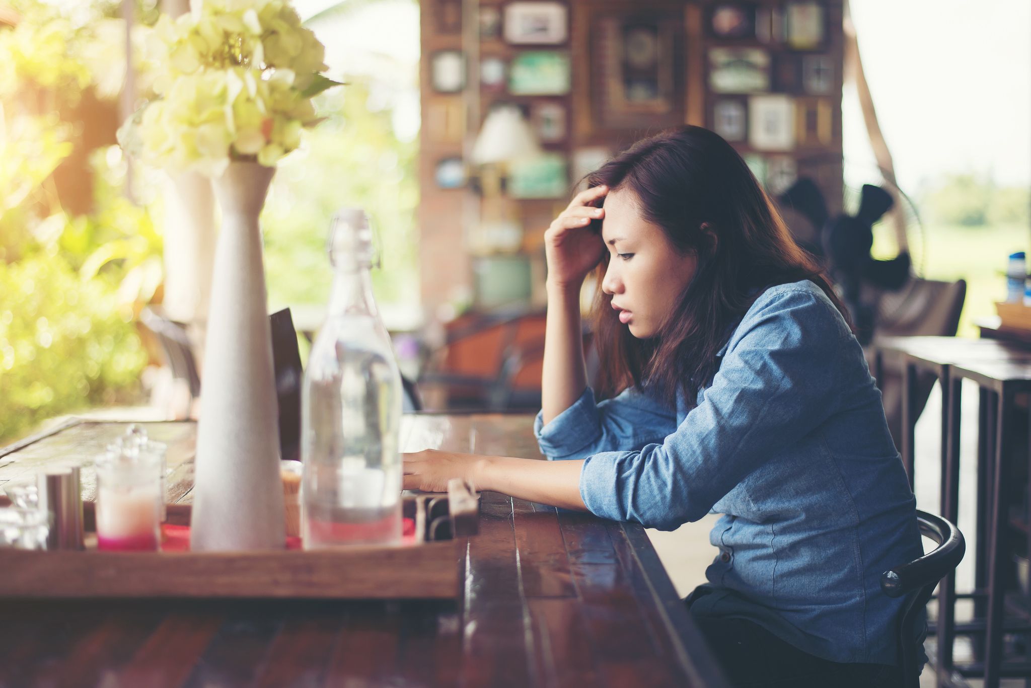 Side View Of Tensed Young Woman Sitting At Cafe