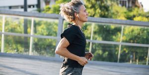 Side view of woman jogging while listening music at bridge