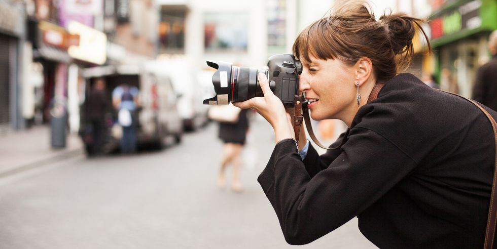 Side view of woman photographing on city street