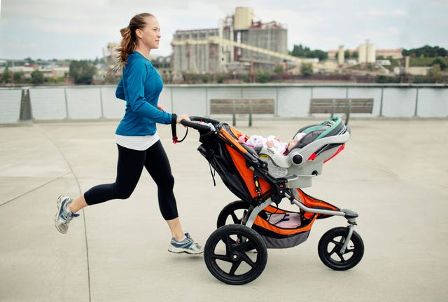side view of woman pushing baby stroller while jogging in city