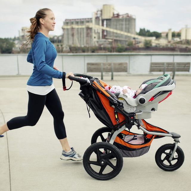 side view of woman pushing baby stroller while jogging in city