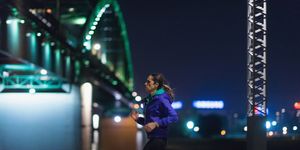 side view of woman running by river at night