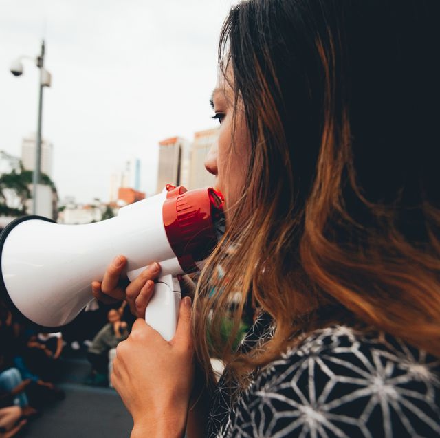 side view of woman talking on megaphone on city street