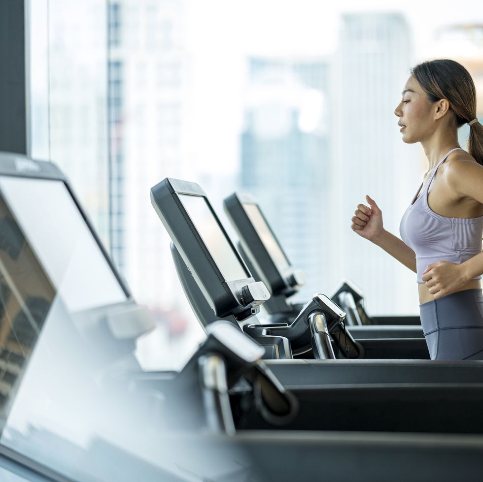 side view of young asian women athlete running or jogging on treadmill in a hotel sport club