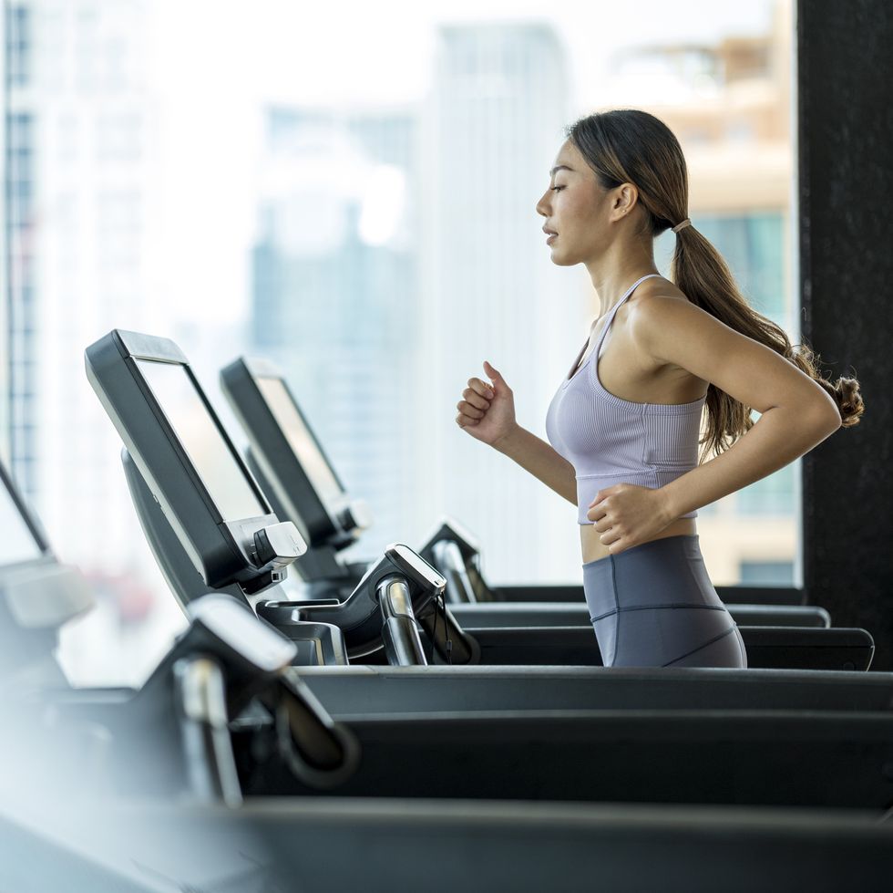 side view of young asian women athlete running or jogging on treadmill in a hotel sport club