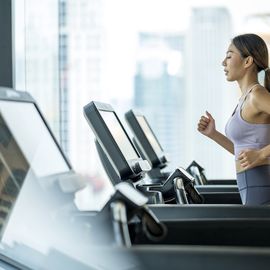 side view of young asian women athlete running or jogging on treadmill in a hotel sport club.