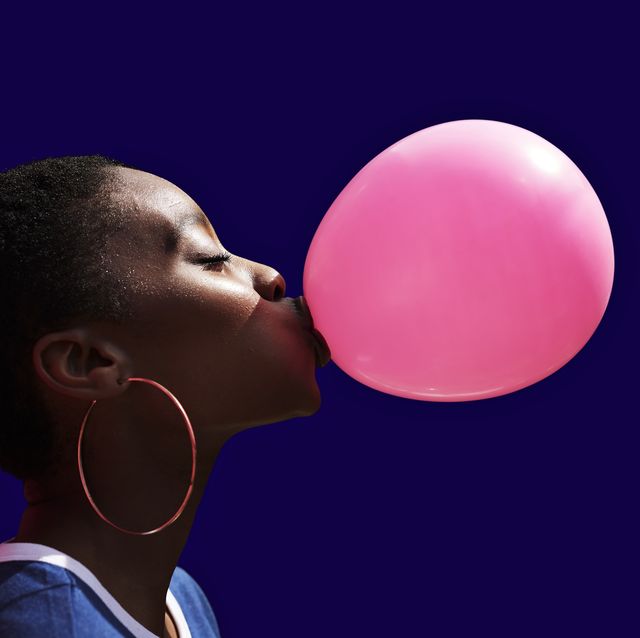 side view of young woman blowing balloon
