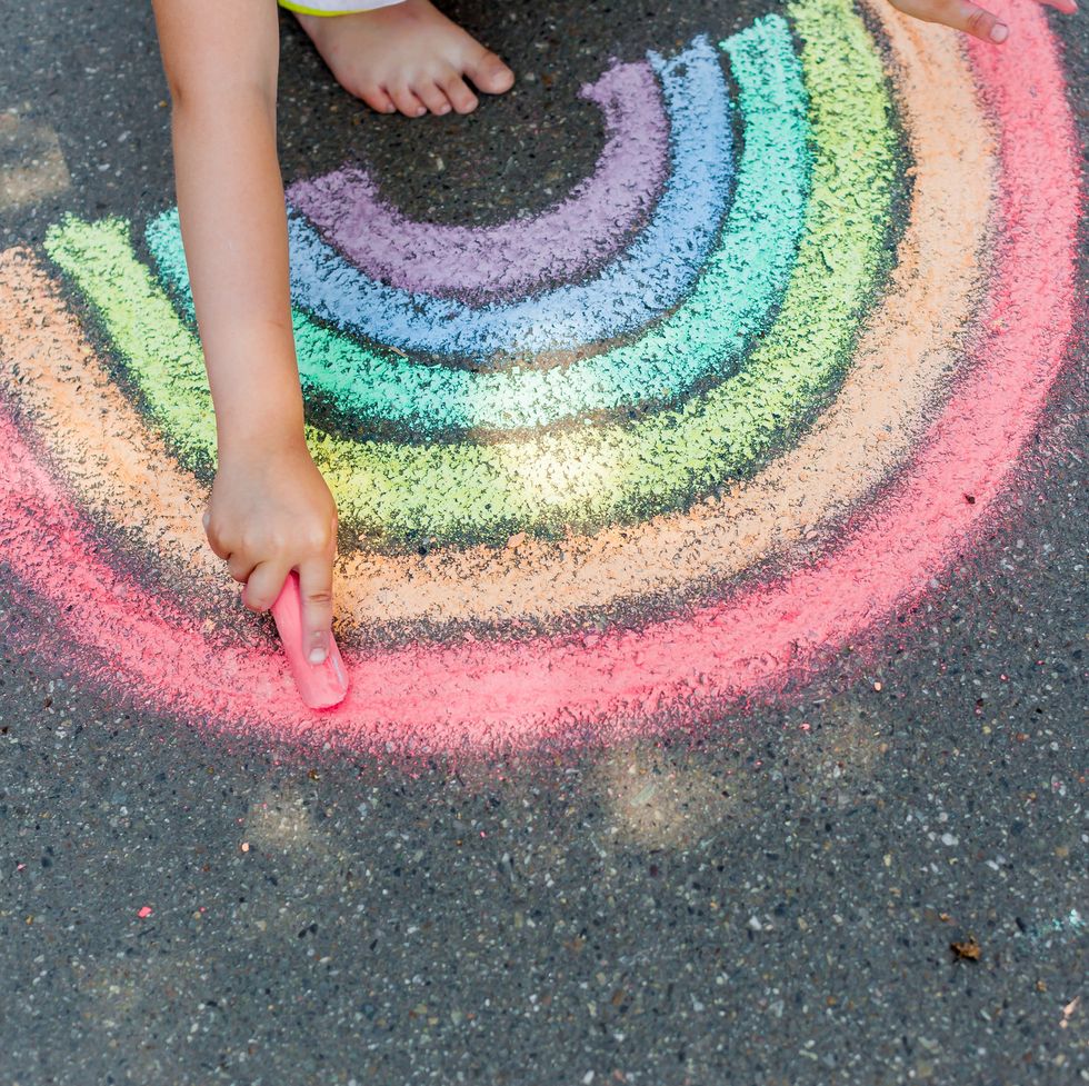 the child girl draws a rainbow with colored chalk on the asphalt child drawings paintings concept education and arts, be creative when back to school
