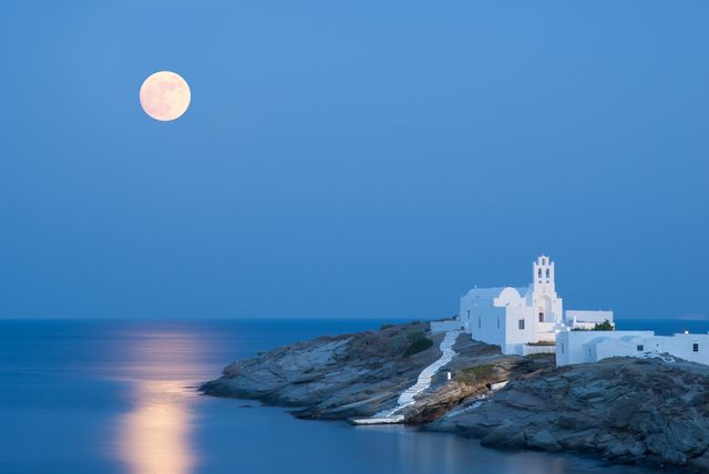 a summer picture of the island sifnos with the full moon and its reflections on the aegean sea the famous church of panagia chrysopigi on the foreground