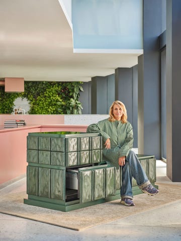 woman sits on modular fridge covered in tiles