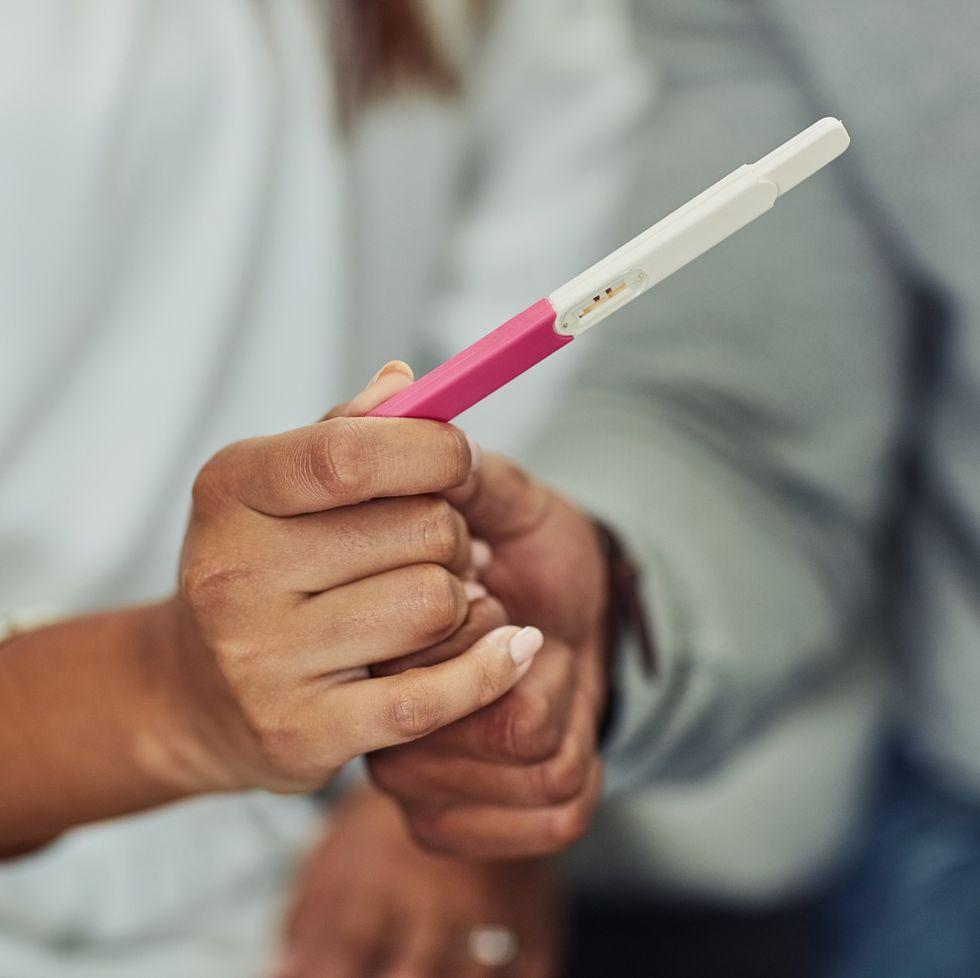 Parents holding hands and a pregnancy test.