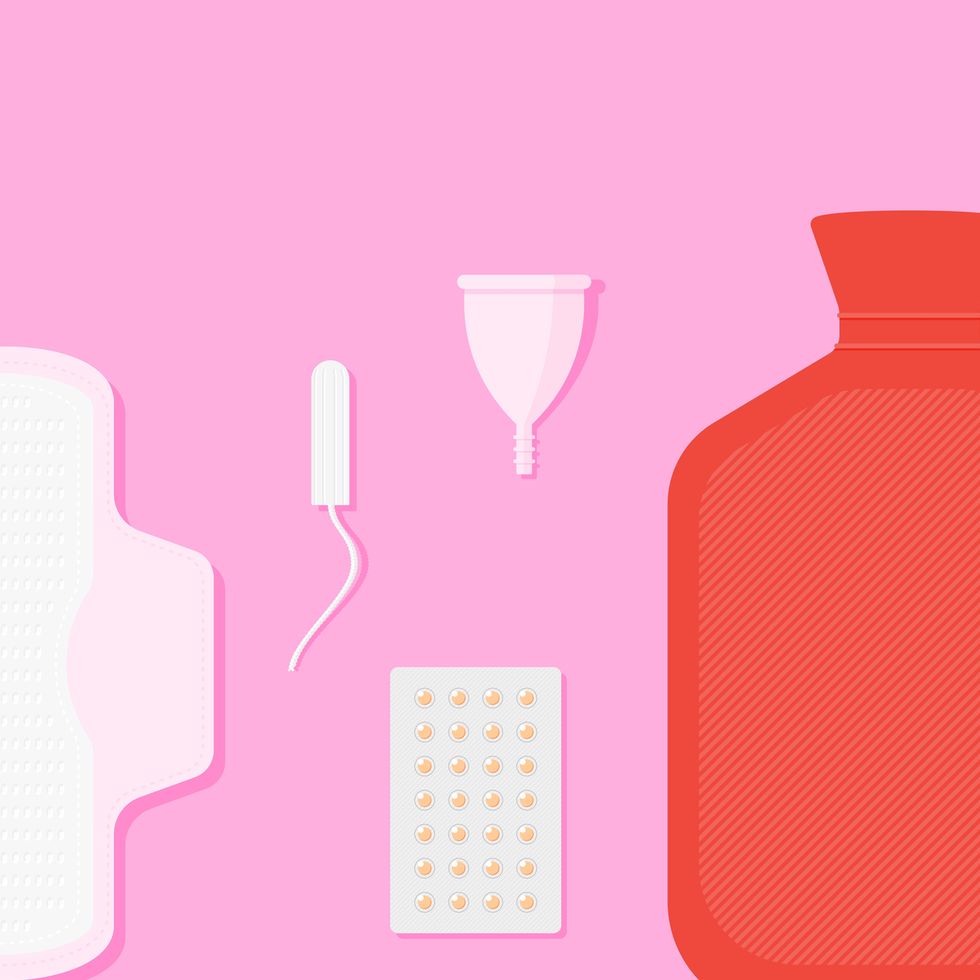Menstrual pad, tampon, reusable period cup and hot water bottle on pink surface.