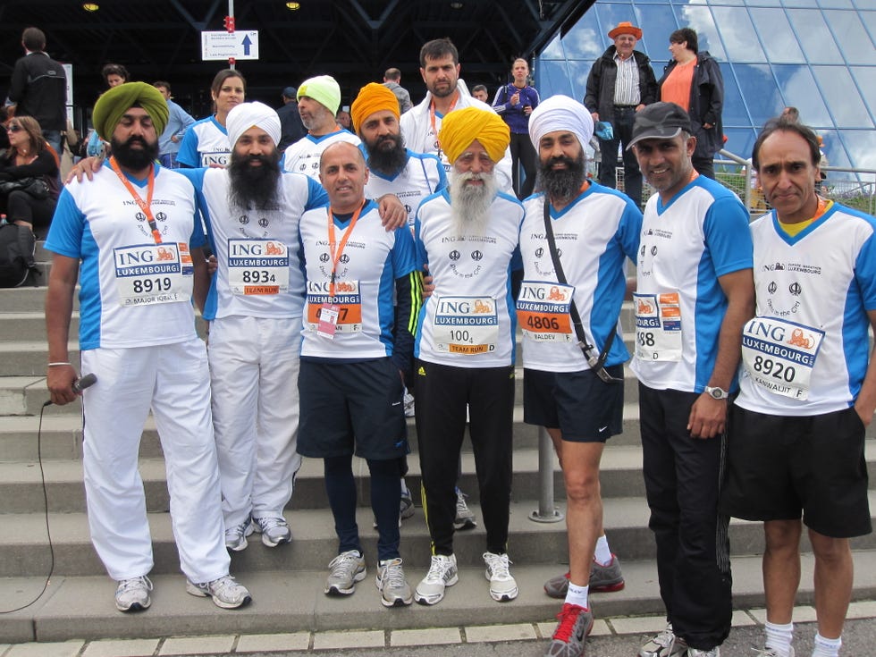 group of runners pictured together standing on some steps, the remarkable fauja singh centre, with members of sikhs in the city