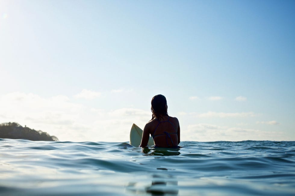 female surfer straddling surfboard in blue ocean