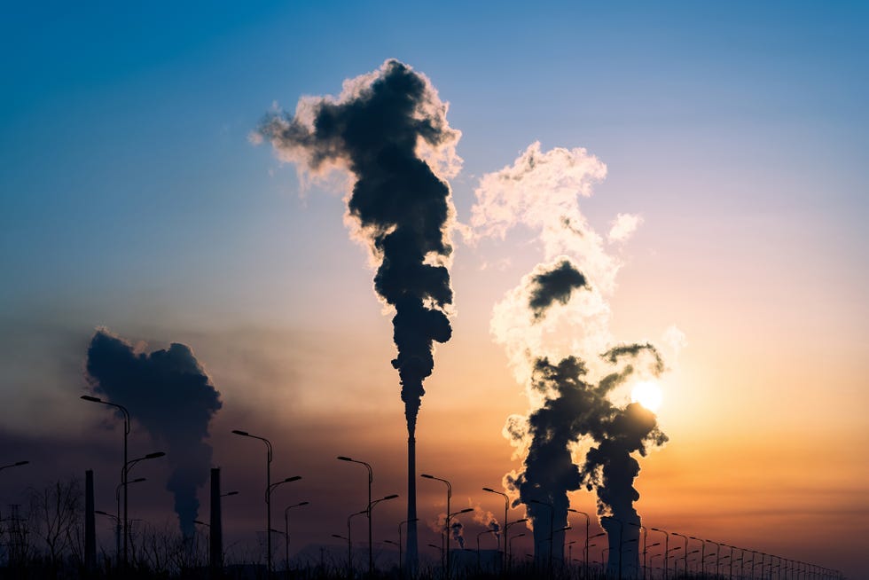 silhouette of a high industrial pipe with the sun behind it