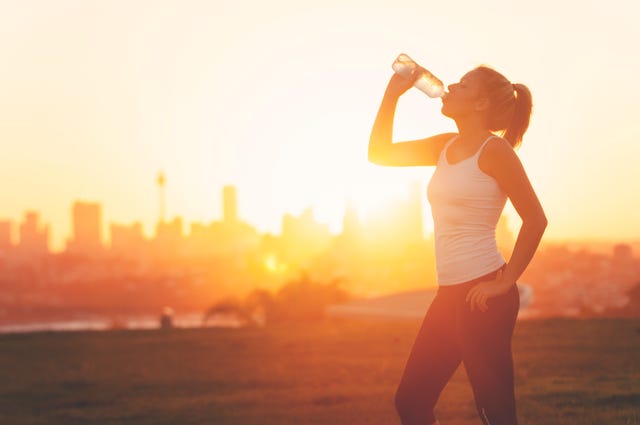 silhouette of a woman drinking form a cold water bottle