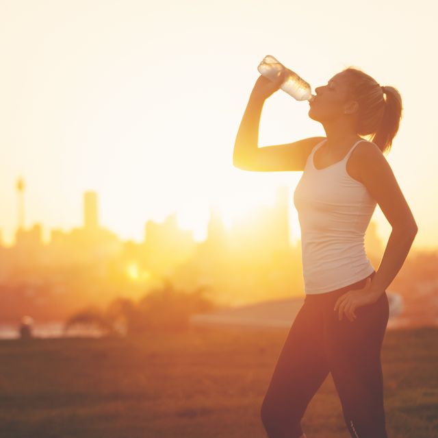 silhouette of a woman drinking form a cold water bottle