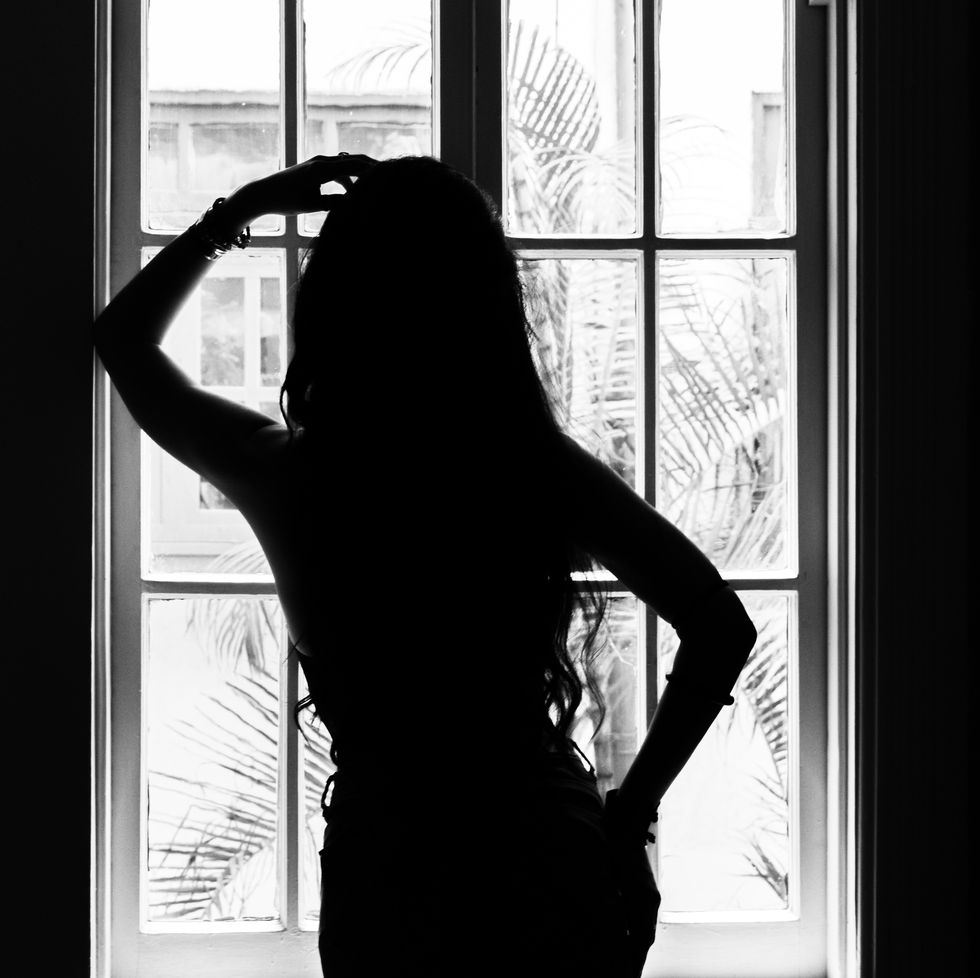 silhouette of a young mexican woman against a window