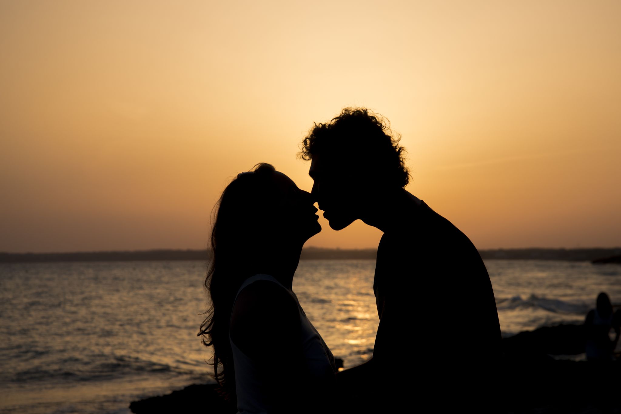 silhouette of couple kissing at sunset on the beach