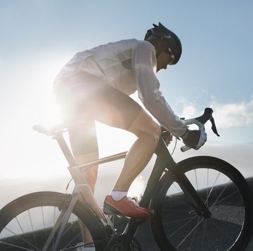 silhouette of cyclist riding up in high mountains at sunrise