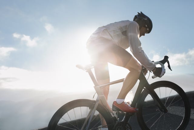 silhouette of cyclist riding up in high mountains