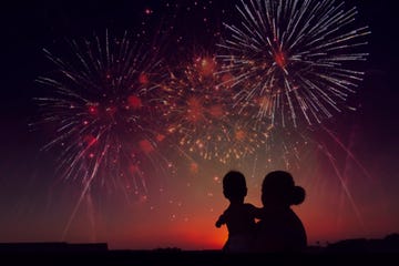 madre con nino viendo fuegos artificiales de espaldas