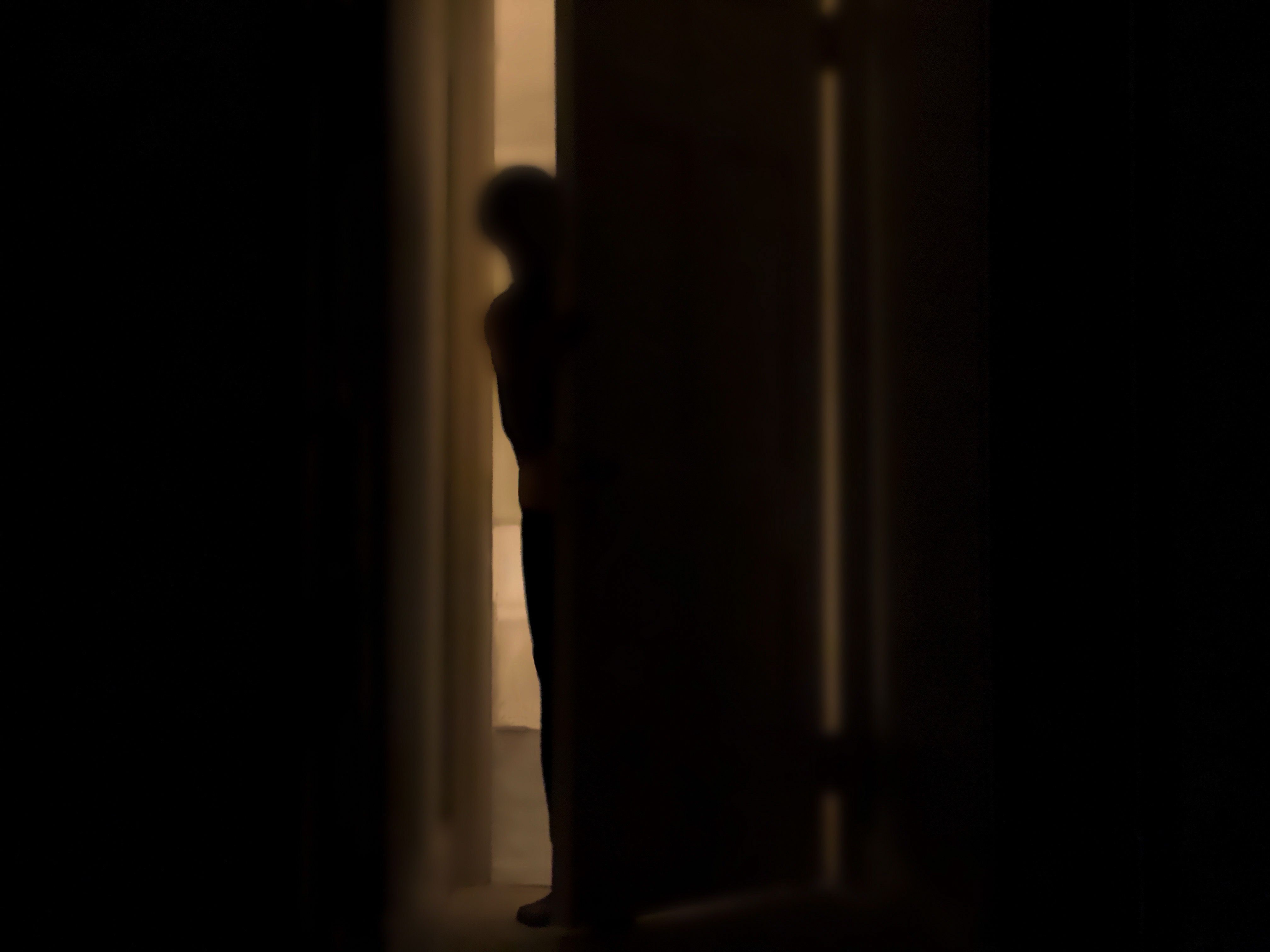 https://hips.hearstapps.com/hmg-prod/images/silhouette-of-person-peeking-into-dark-room-through-royalty-free-image-1686773134.jpg