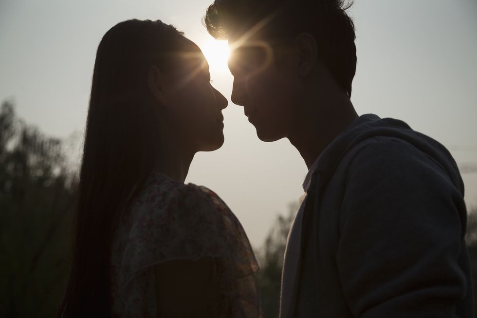 silhouette of young couple very close to each other, sunbeam and lens flare