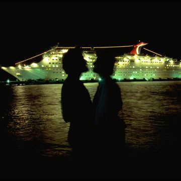 couple embracing in front of cruise ship