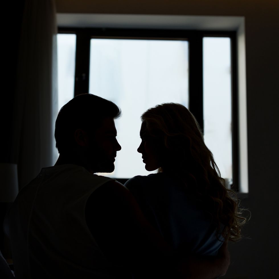 silhouettes of heterosexual couple looking at each other in dark room
