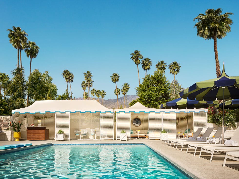 a swimming pool with lounge chairs and umbrellas by it