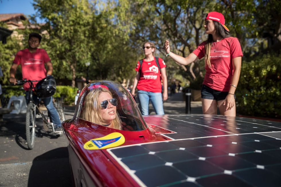 Maggie Ford hoofd engineering van het Stanford Solar Car Project toont samen met haar team een zonneauto op een activiteitenbeurs van Stanford University