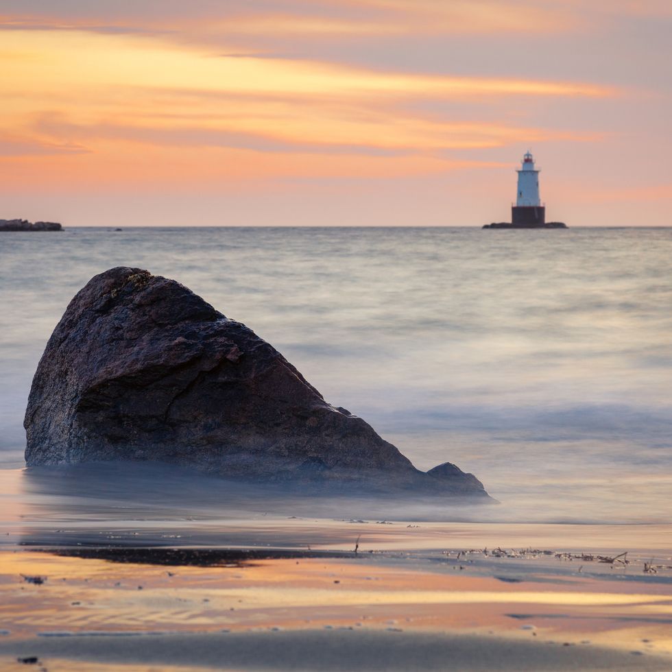 silky water rocky sunset seascape with lighthouse