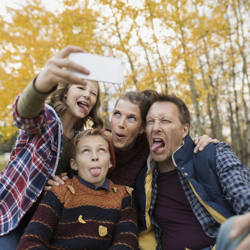 Silly family taking selfie making faces autumn park