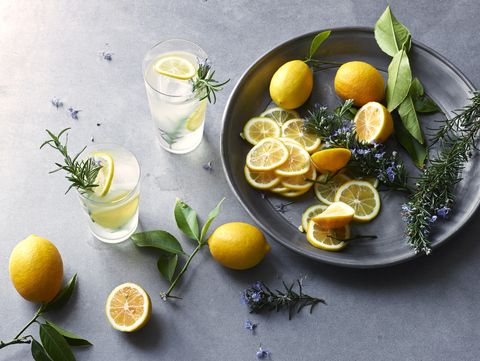 still life of freshly cut lemons and lavender on a pewter tray with glasses of iced lemonade