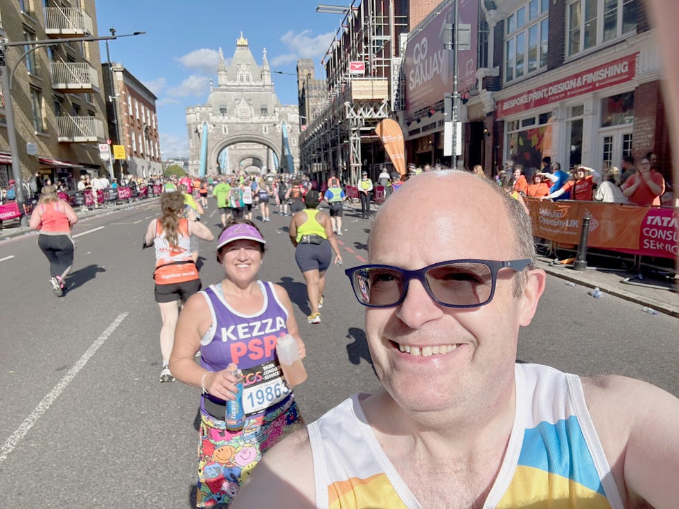 smiling runners taking part in the london marathon, close to tower bridge