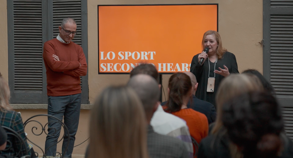 a woman speaking into a microphone to a man in front of a crowd