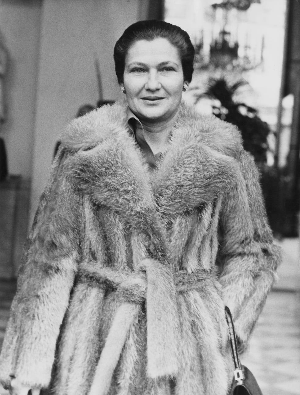 simone veil smiles at the camera, she wears a fur coat and earrings