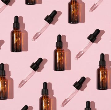 simple face skincare pattern made with dark brown glass serum or essential oil bottle and dropper on pastel pink background minimal fresh product aesthetic