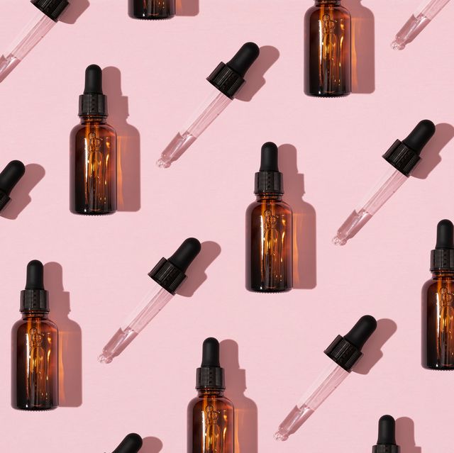 simple face skincare pattern made with dark brown glass serum or essential oil bottle and dropper on pastel pink background minimal fresh product aesthetic